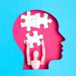 a pink toy figurine holding a puzzle piece inside the silhouette of a head