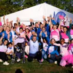 Team ALGSO at the Broschtkriibslaf 2026 in Hesperange, all gathered and raising their hands in the air.